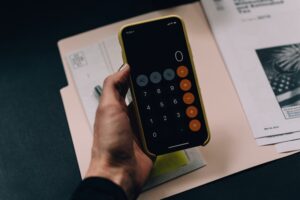 Calcul de l'épargne retraite sur smartphone avec calculatrice et documents financiers pour préparer sa retraite